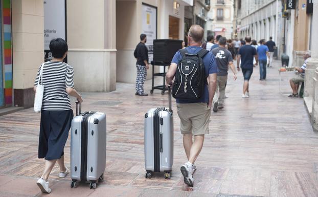 Turistas, con sus maletas, se adentran en el centro de Málaga en busca de su alojamiento. 