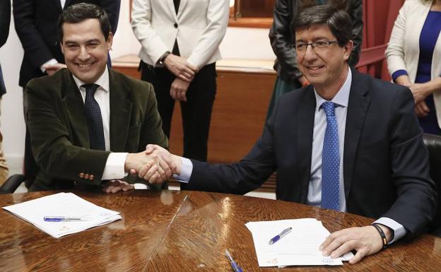 Juanma Moreno y Juan Marín se estrechan la mano ayer en el Parlamento andaluz tras sellar su acuerdo. 