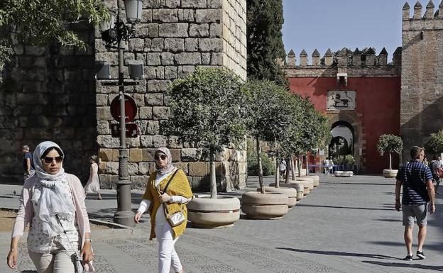 Turistas pasean junto al Real Alcázar de Sevilla. 
