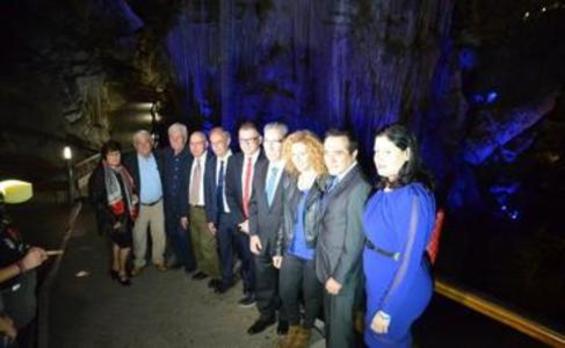 Descubridores y autoridades, este martes en la Cueva de Nerja, junto a la gran columna central, iluminada de azul.