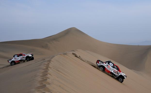 Dos vehículos atraviesan una duna durante el Dakar 2019.