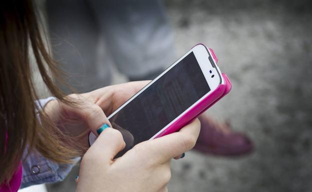 Una joven consulta whatsapp en su móvil. 