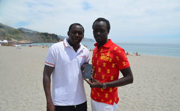 Moustapha y Makhtar Diop, en la playa de Burriana mostrando una foto de su hermana en el teléfono. 