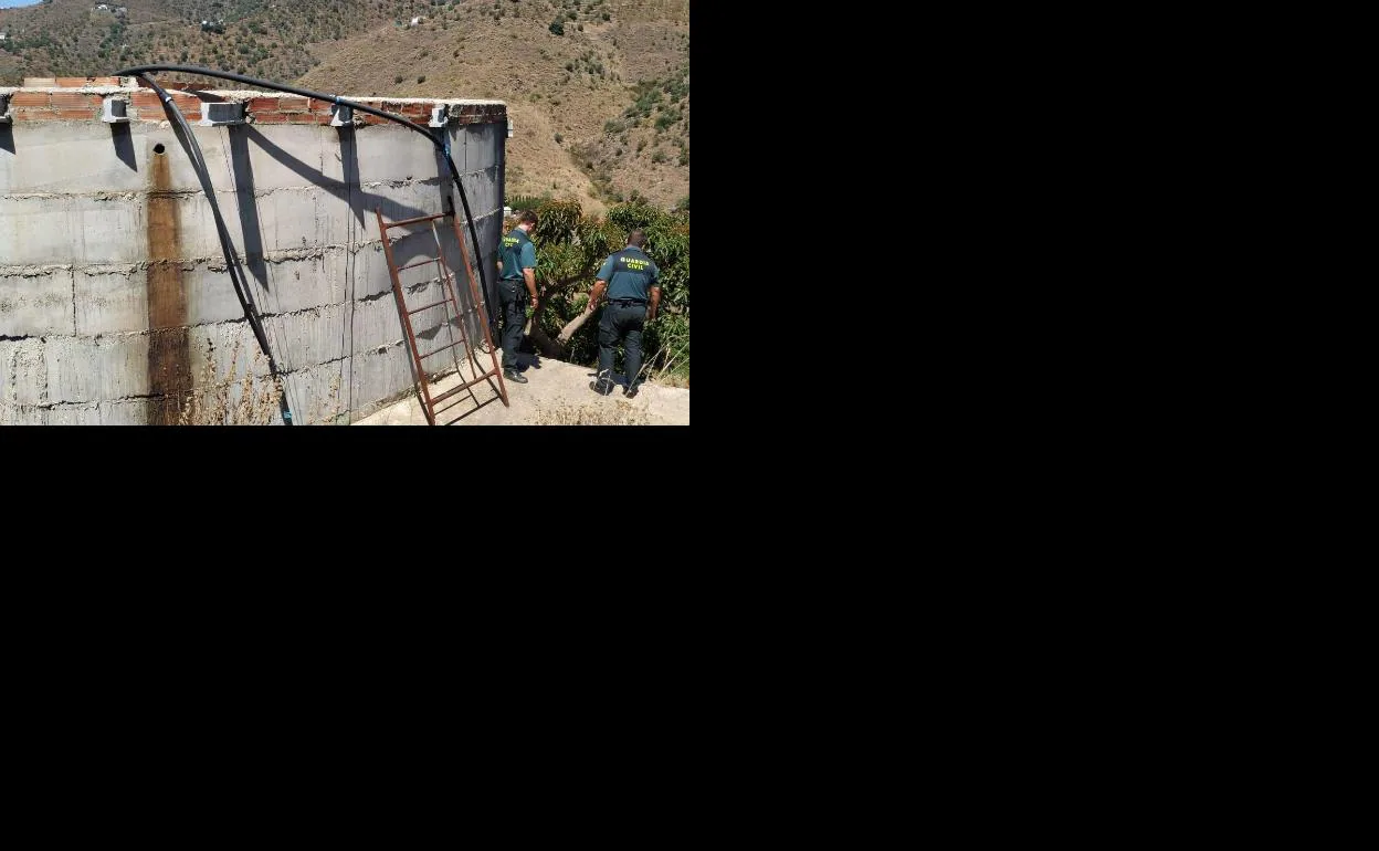 Dos agentes del Instituto Armado, ayer junto a un depósito de agua en una zona rural de la localidad axárquica, cerca de Bentomiz.