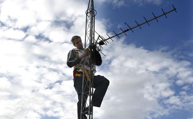 Un técnico revisa el estado de una antena de televisión en un edificio.