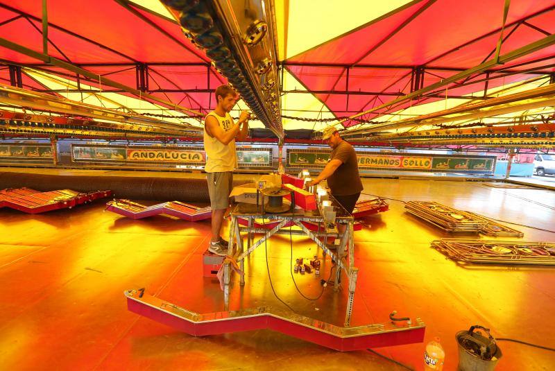 Feriantes, operarios municipales y de contratas y peñistas llevan semanas afanados en poner a punto todos los elementos que conforman esa ciudad efímera que es el Real de Cortijo de Torres.