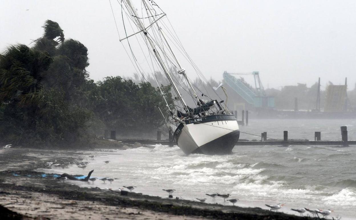 Un velero arrastrado hasta la costa por las olas.