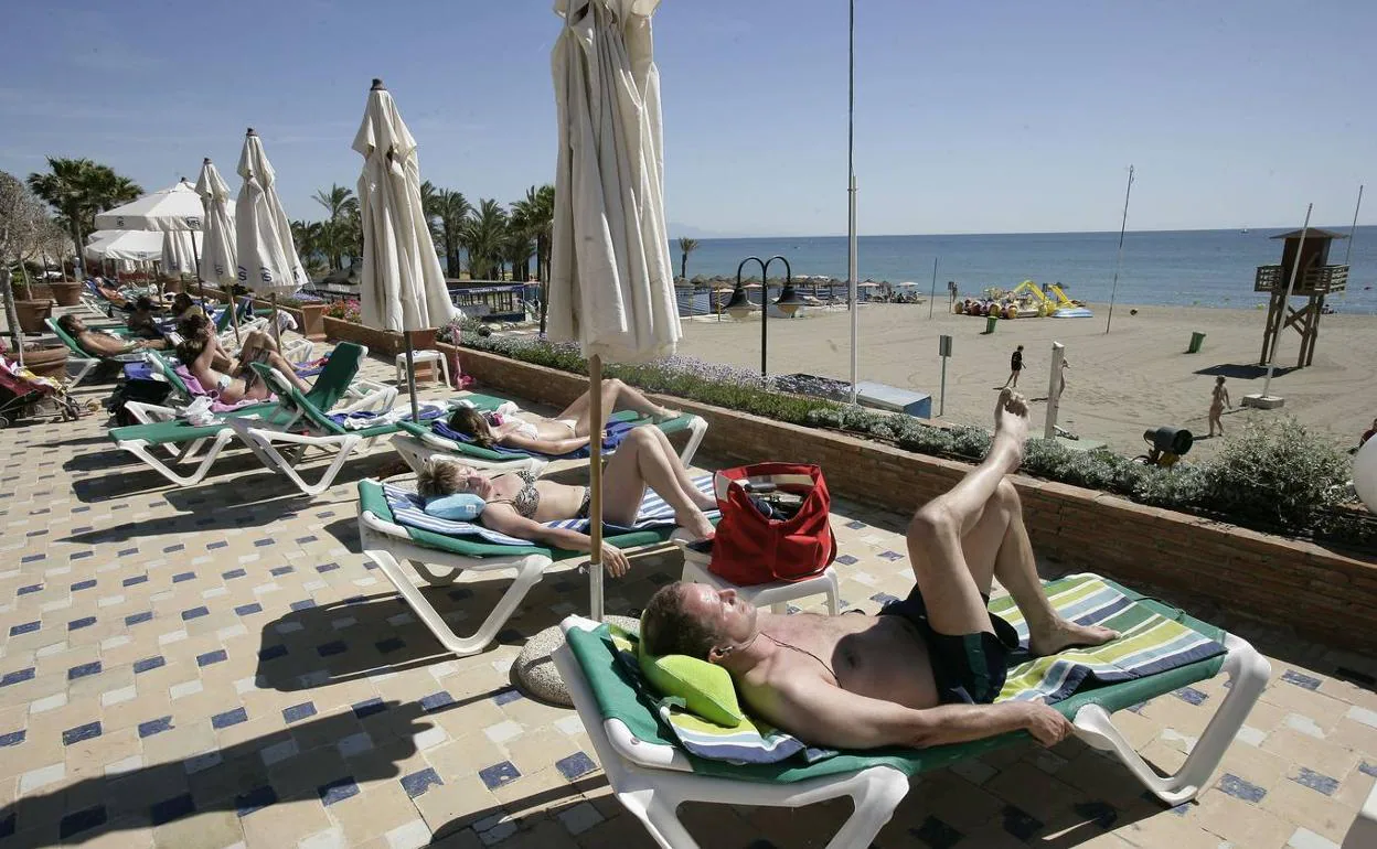 Turistas toman el sol en la terraza de un hotel. 