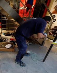 Imagen secundaria 2 - Arriba, una pintada en una calle de Barcelona. Abajo, operarios tratan de reparar los destrozos en una tienda. 