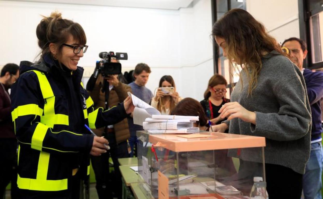 Una funcionaria de correos entrega a la presidenta de una mesa electoral un paquete de votos