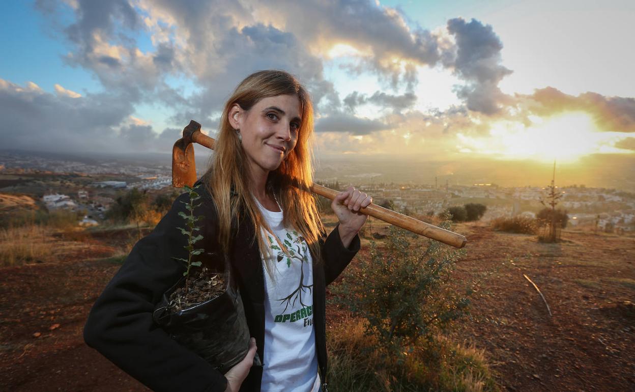 Beatriz Sánchez, fundadora de Operación Encina, posa con su azada y un plantón en el monte de Huétor Vega (Granada) donde crece su bosque. :