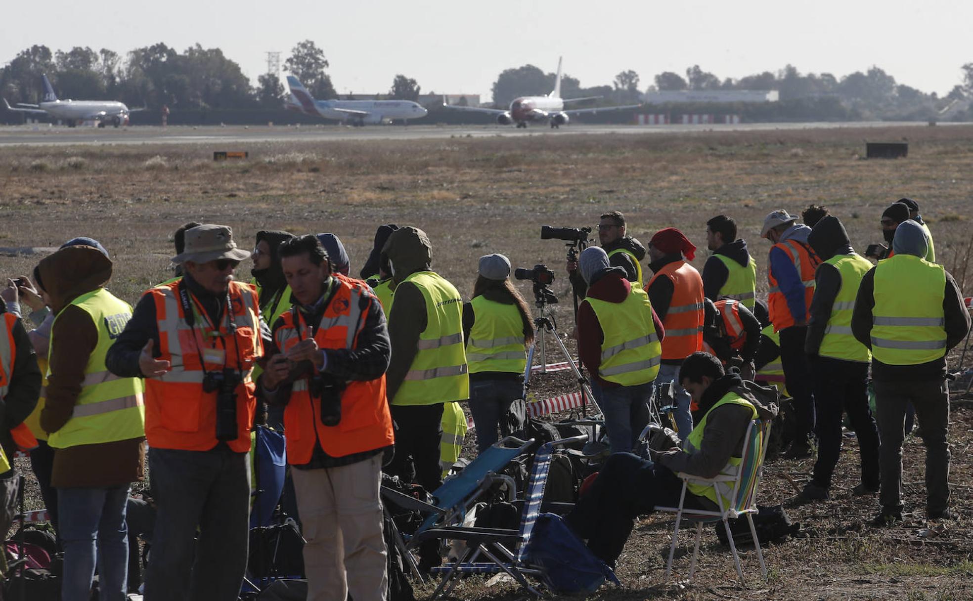 Un nutrido grupo de 'planespotters' se encuentra a pocos metros de la pista del aeropuerto de Málaga para hacer fotos a los aviones. 