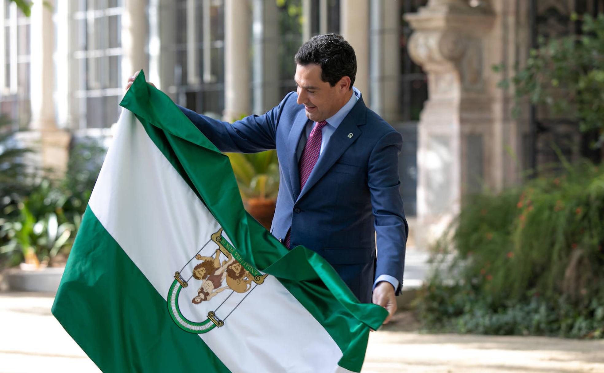 Juanma Moreno con la bandera andaluza en los jardines del Palacio de San Telmo, sede de la Presidencia de la Junta. 