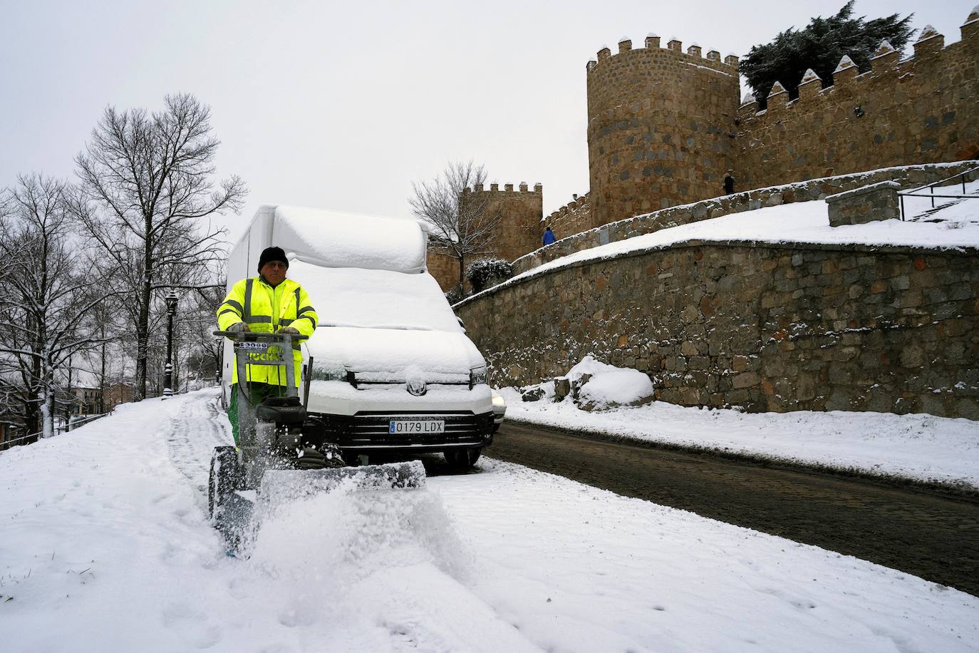 Un operario retira la nieve junto a la muralla de Ávila.