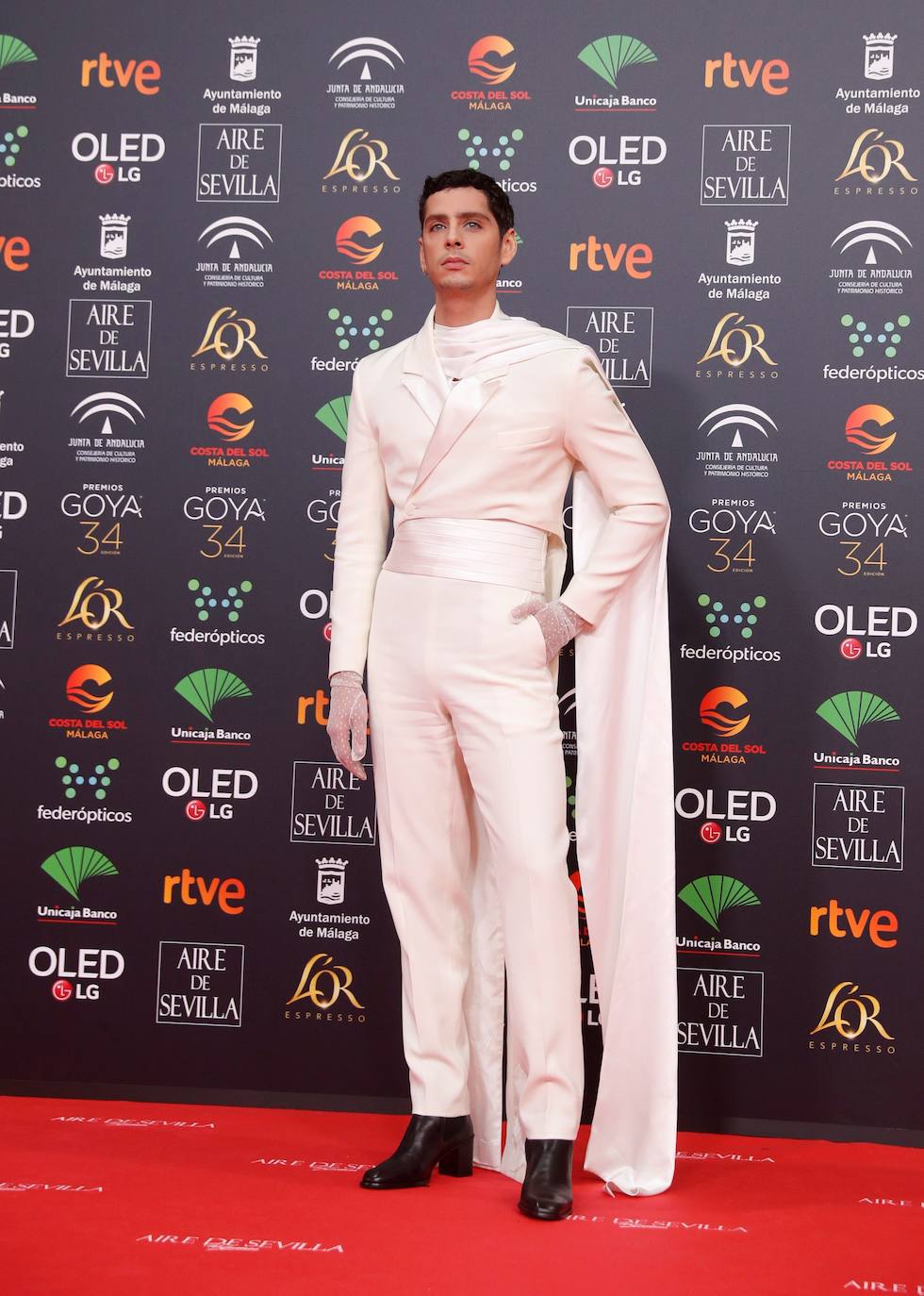 Eduardo Casanova sorprendió otro año más pero esta vez con un sofisticado traje que aunque excéntrico convenció. Un chaqué blanco, con solapas asimétricas, fajín de seda y capa de Mans Concept. Completó el look con guantes de plumeti y botines. 