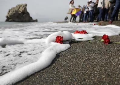 Imagen secundaria 1 - La imagen superior muestra a los asistentes al acto de homenaje en el lugar de la placa conmemorativa a las víctimas de la carretera Málaga-Almería. Por debajo, unas rosas flotando en la orilla y una mujer que ha acudido al acto. 