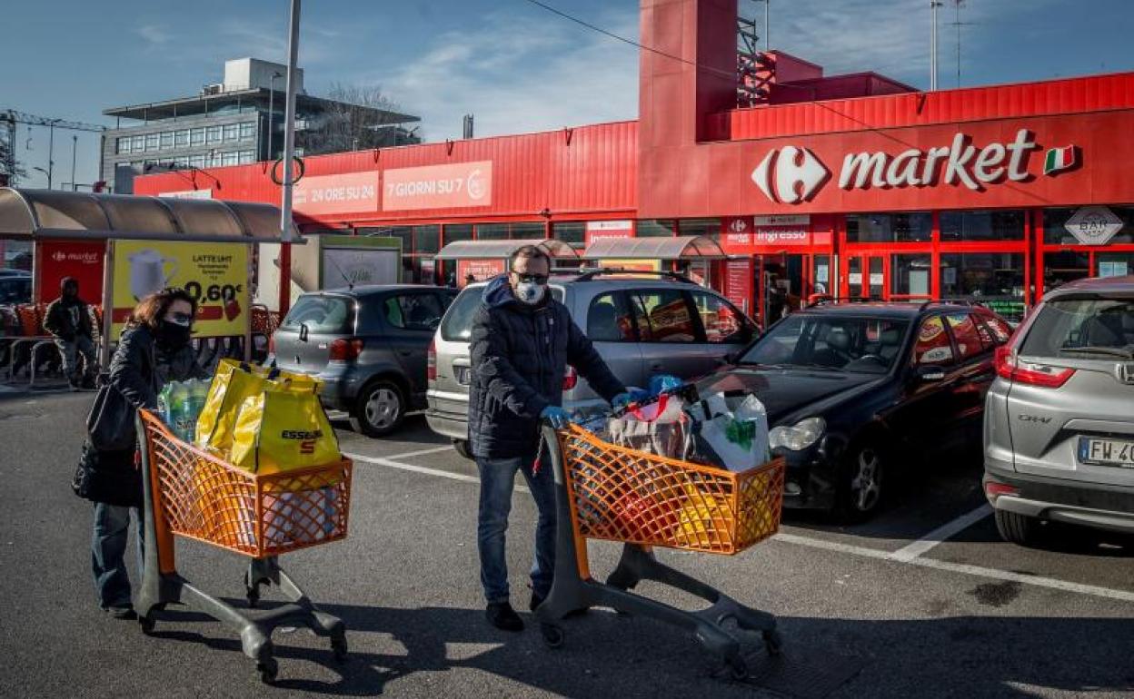 Dos personas hacen acopio de alimentos en Milán.