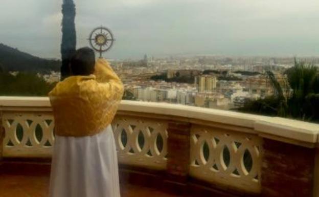 El rector del Seminario, dando la bendición con el Santísimo a la ciudad desde una terraza del edificio. 