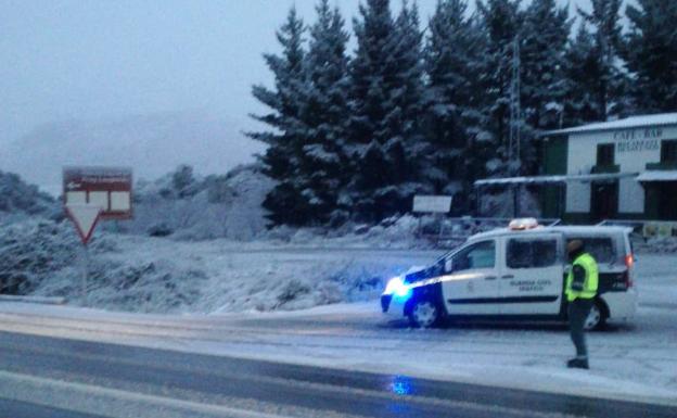 Un agente de la Guardia Civil vigila la carretera afectada por la nevada. 