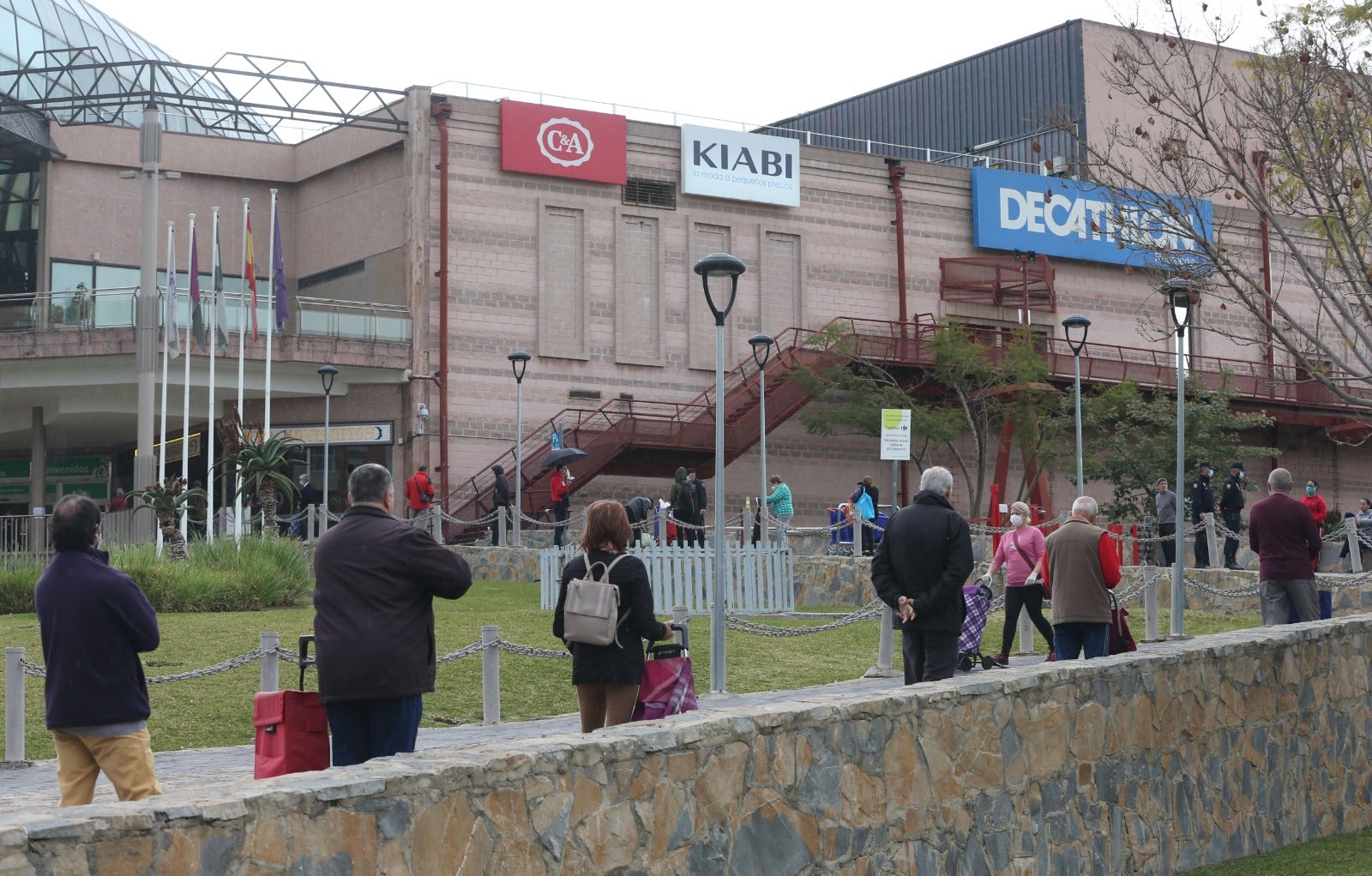 Ciudadanos hacen cola para acceder al centro comercial Rosaleda, en Málaga capital.