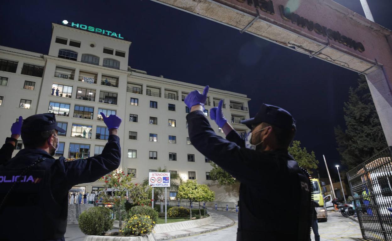 Dos policías saludan al personal del Hospital Regional de Málaga. 