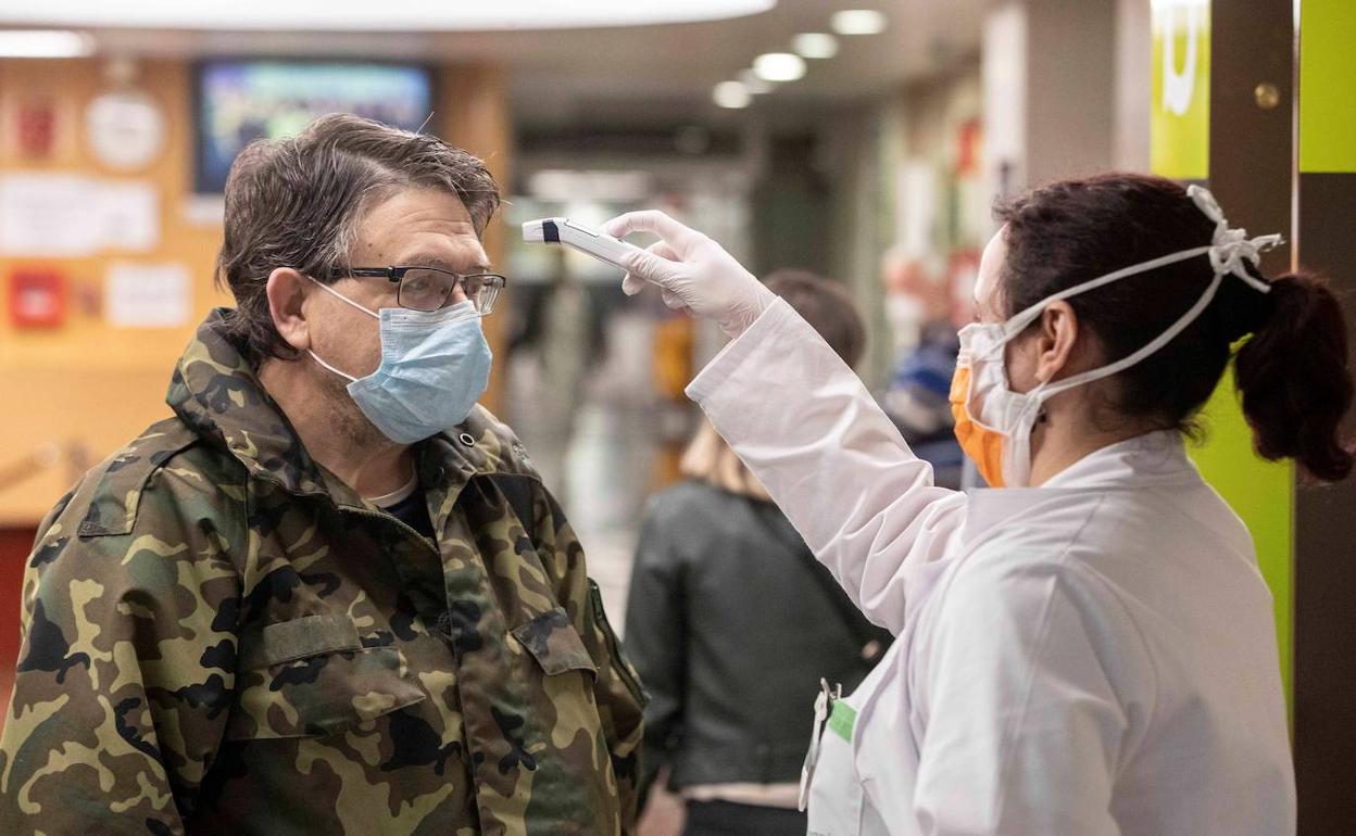 Una enfermera mide la temperatura a un militar.