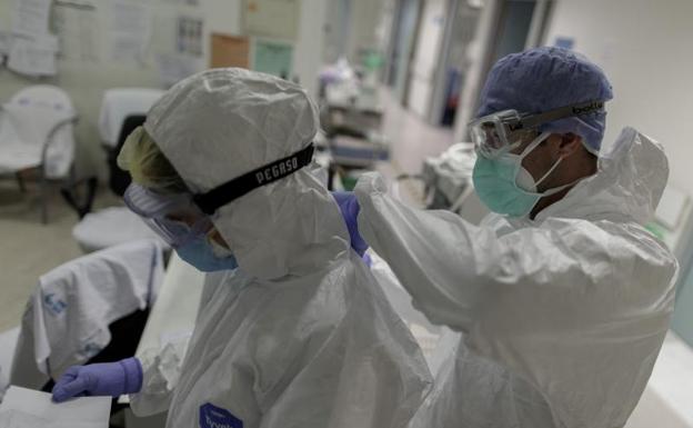 Un trabajador sanitario pinta a otro el nombre en su bata para que los pacientes le identifiquen en la Unidad de Cuidados Intensivos. 