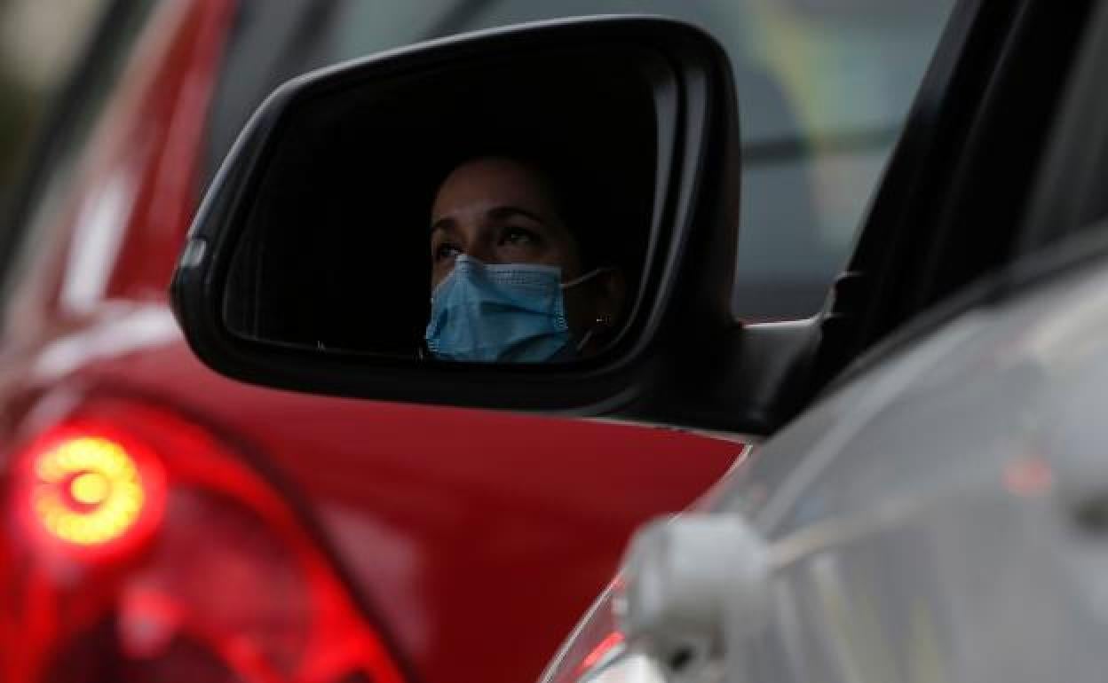 Una conductora en el interior de su coche protegida con una mascarilla