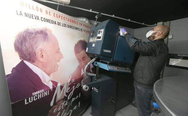 Juan Luis Artacho revisa un proyector, junto al cartel de 'Lo mejor está por llegar'