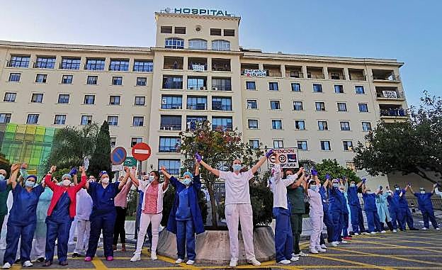 Trabajadores delante del Hospital Regional unen sus manos tras el aplauso. 
