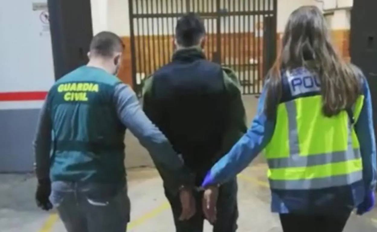 Un guardia civil y una policía nacional custodian a uno de los cinco detenidos. 