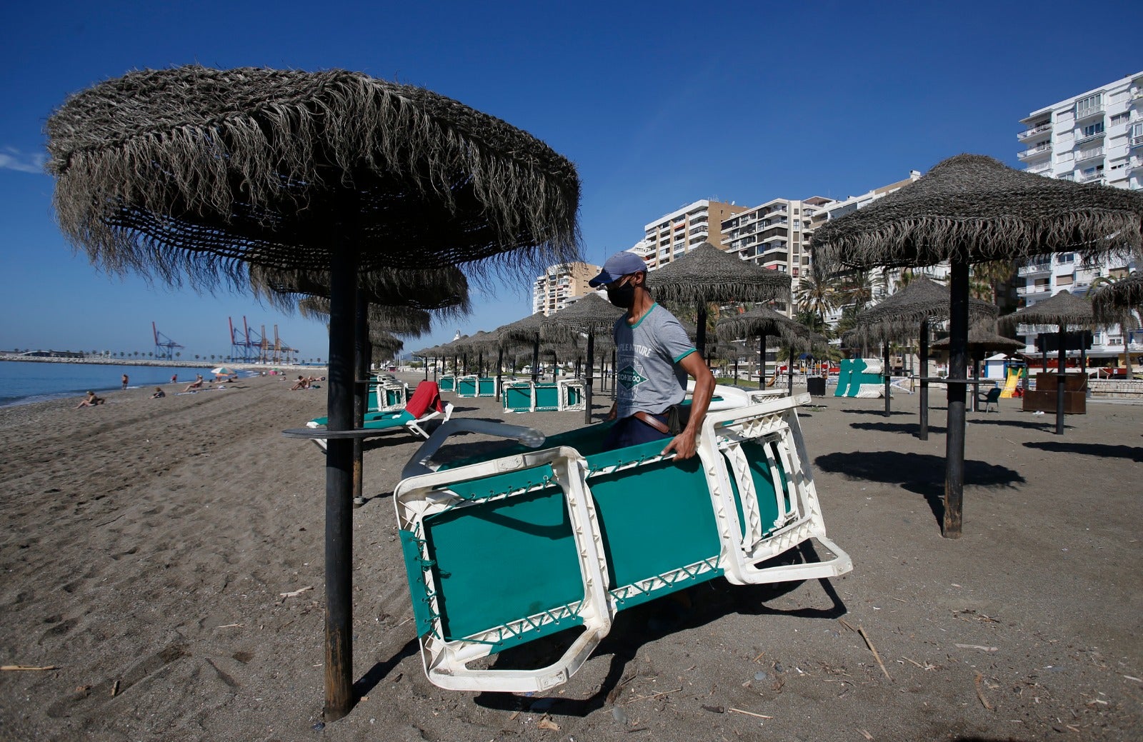 El empleado de un chiringuito dispone las hamacas en la playa.