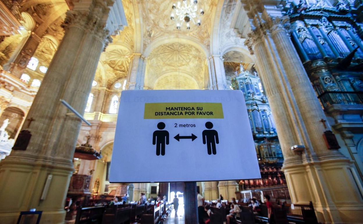 Cartel colocado en la Catedral de Málaga para recordar a los fieles que deben guardar las distancias de seguridad. 