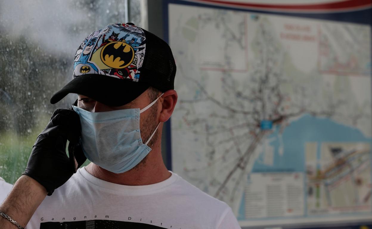 Un joven habla por el móvil con la mascarilla puesta. 