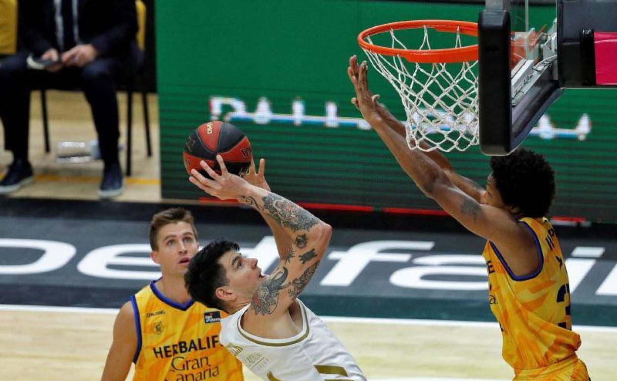 El alero argentino del Real Madrid, Gabriel Deck, trata de lanzar a canasta ante el escolta estadounidense del Herbalife Gran Canaria, Demonte Harper