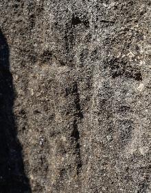 Imagen secundaria 2 - Arriba, Francisco Marmolejo señala un muro del alcázar de Bobastro con un estilo constructivo precedente de Medina Azahara. Abajo, talla con el rostro del sublevado Ibn Hafsún y una cruz bajorrelieve en piedra en el yacimiento malagueño.