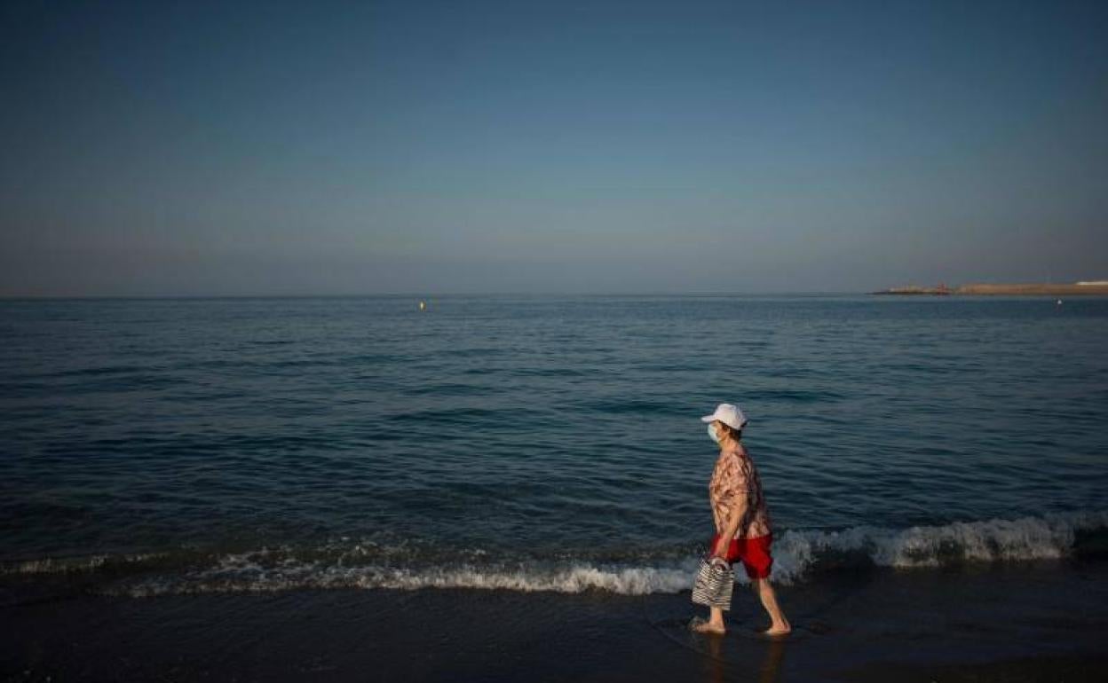 Una mujer pasea por una playa de Adra, donde se han registrado dos nuevos casos.