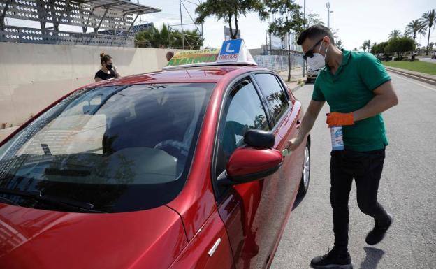 Un profesor de autoescuela limpia el coche antes de una clase práctica con alumnos en la capital malagueña el pasado 1 de junio. 