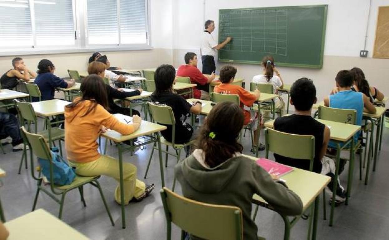 Alumnado, atendiendo a un profesor en clase. 