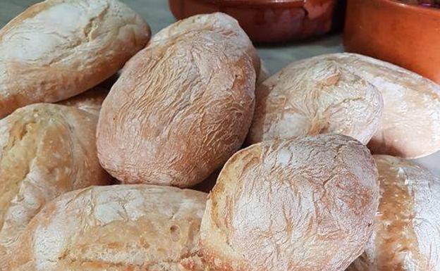 Imagen principal - Los molletes los compra, encarga y recoge en Cuevas Bajas. Abajo, molletes de queso de cabra con tomate seco y de 'pringá' de berzas y terraza de El Huesca, en calle Cañón, junto a la Catedral de Málaga.