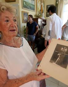 Imagen secundaria 2 - Arriba, Remedios posa con su extensa familia en segundo término. En sus manos sostiene una fotografía de calle Larios de 1937, año en que se mudó a la calle. Abajo, a la izquierda, en el comedor de su casa, que hace años acogió la consulta de su hermano, Adolfo. Al lado, Remedios muestra una fotografía suya, cuando tenía 18 años 