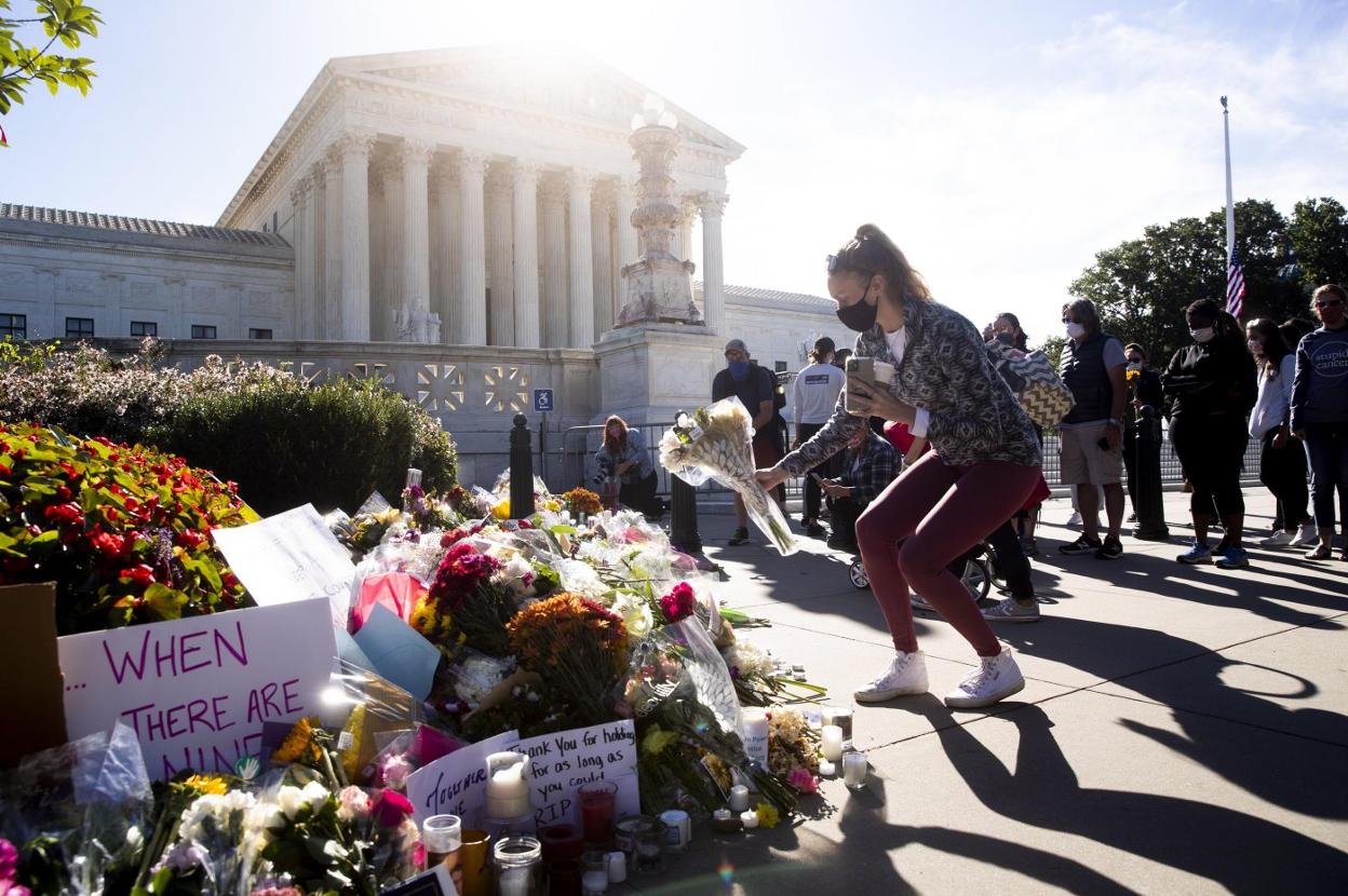 Una joven coloca un ramo de flores en un memorial en recuerdo a la magistrada Ruth Bader Ginsburg, fallecida el viernes. M. REYNOLDS / Efe