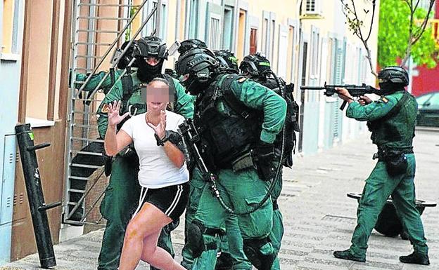 Imagen principal - Por sorpresa: Un agente se lleva a la mujer de un sospechoso mientras sus compañeros aseguran el interior. Todo a punto: Los mandos reparten las fichas de los objetivos en una explanada situada a las afueras de Algeciras. Efectuarán 40 registros en tres tandas, muchos simultáneos para reducir la capacidad de reacción del narco.Soluciones imaginativas: Narcoembarcadero camuflado tras una fachada corredera en la playa de Puente Mayorga. 