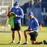 El entrenador del Málaga, Sergio Pellicer, con una rodilla en el césped y junto al segundo técnico, Manuel sánchez, planificando un entrenamiento.