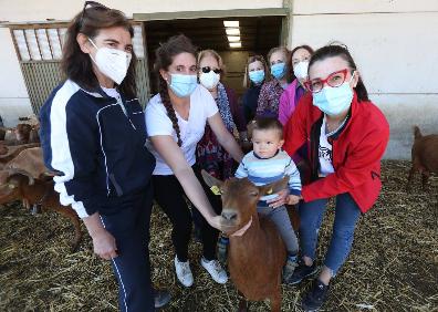 Imagen secundaria 1 - Arriba, las mujeres en uno de los tractores de la empresa de Resu (subida en él). Abajo, a la izquierda, el pequeño Miguel Ángel posa en una de las cabras de la explotación de Beatriz. Al lado, el grupo en uno de los rincones de La Joya, donde nacieron y donde han decidido quedarse