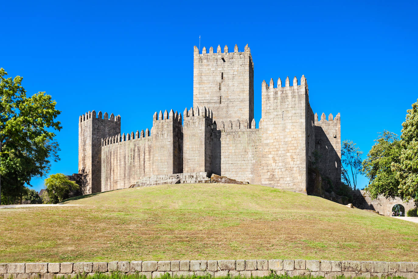 Castillo de Guimarães (Portugal). Está considerado la fortaleza medieval más importante del norte de Portugal. La presencia del castillo evoca la mezcla de leyenda, poesía y heroísmo que rodea los principios de la historia nacional. Su característica más llamativa son los muros construidos en forma de pentagrama, con ocho torres rectangulares almenadas. Construido en el siglo X, luego se convirtió en la residencia real oficial del Conde D Henrique, el padre del primer rey de Portugal, Afonso Henriques. El castillo resistió la batalla de São Mamede en 1128, que resultó en la victoria de Alfonso y significó el punto de partida de un Portugal independiente. Desde entonces, el castillo ha sido reconocido como el lugar de nacimiento de la nación portuguesa y está considerada una de las Siete Maravillas de Portugal, según detallan desde la web Jetcost.es