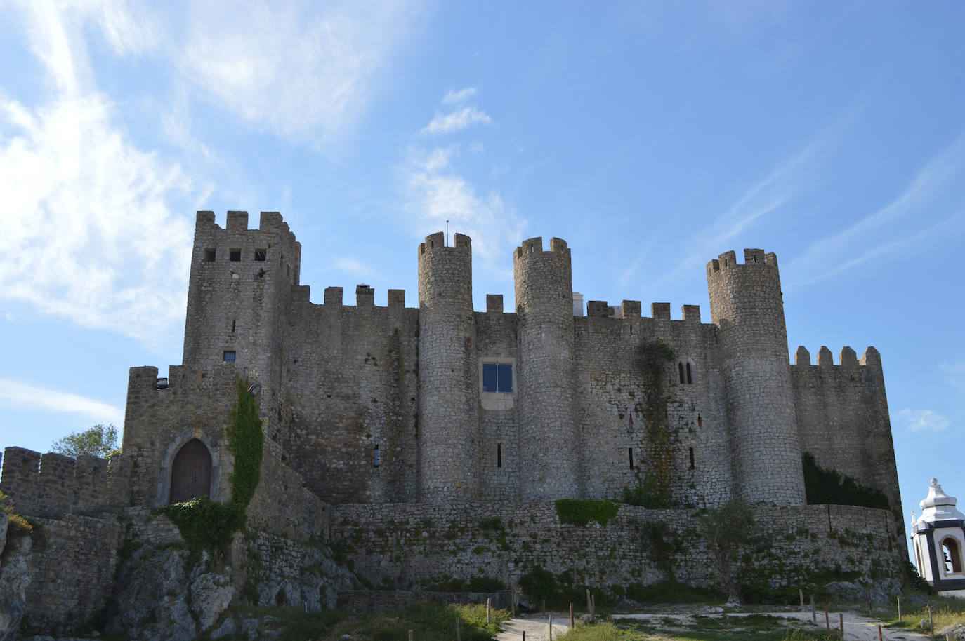 Castillo de Óbidos (Portugal). La construcción de este castillo mágico se remonta a la presencia romana en Portugal. El castillo de Óbidos tiene torres en forma de cilindro y cuadradas, mientras que la piedra caliza y el mármol añaden una faceta grandiosa a la fachada. Es un buen ejemplo de una fortificación bien conservada, y el castillo ha escapado al destino de ser convertido en ruinas, y se ha transformado, según Jetcost.es en uno de los hoteles pequeños más románticos de Portugal. El pueblo que lo rodea, Óbidos, es conocido por sus atractivos paisajes y exuberante vegetación. El que una vez ofreció protección militar en el corazón de Portugal, ahora ofrece como hotel a los visitantes la oportunidad de viajar en el tiempo, según la web Jetcost.es