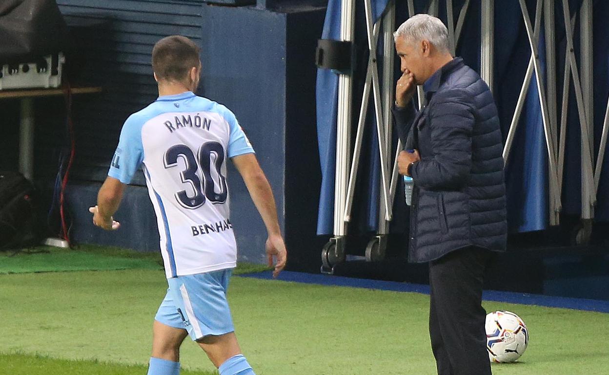 El jugador del Málaga, Ramón, de espaldas, conversa con el técnico, Pellicer, en el partido contra el Sporting. 