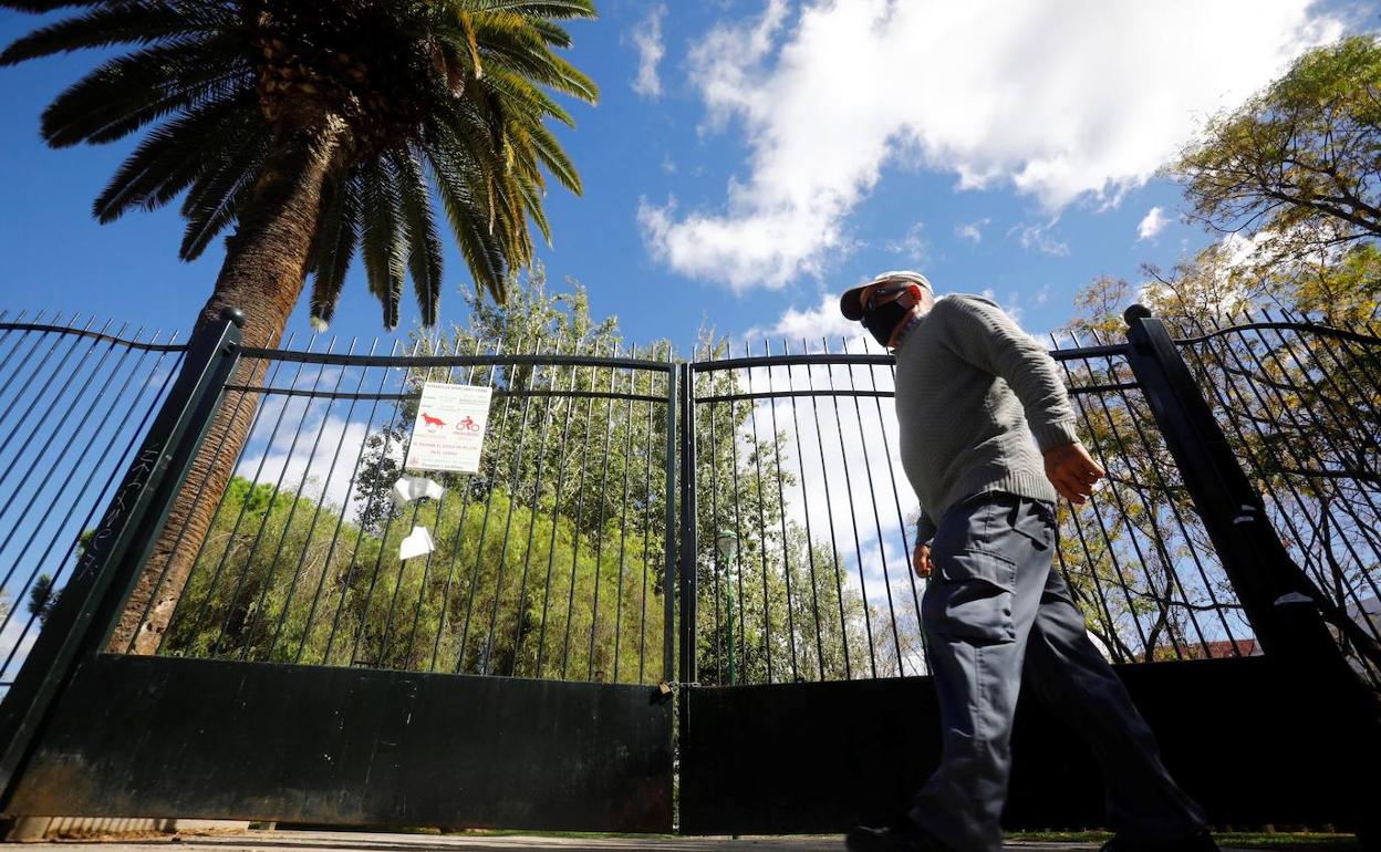 Un hombre pasa junto a las cancelas cerradas de un parque en Córdoba.