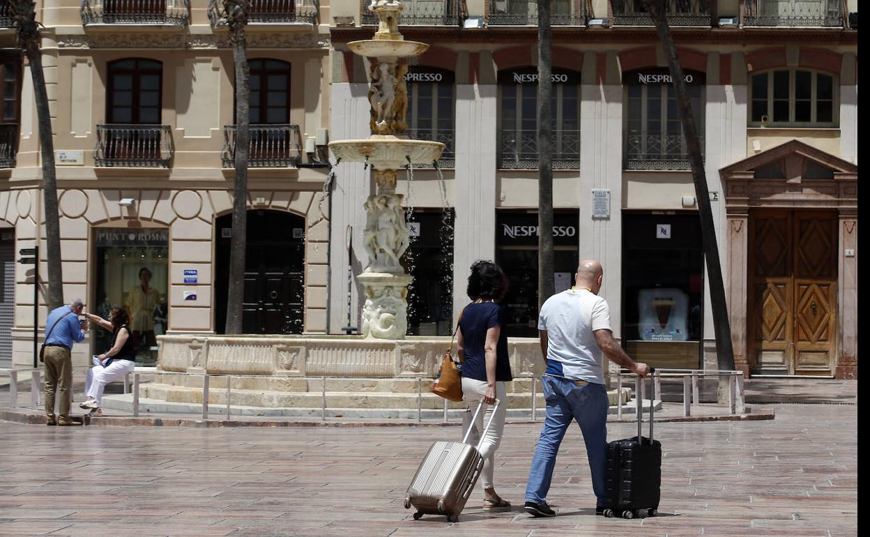 Turistas se dirigen por el Centro de la capital de la Costa del Sol hacia su alojamiento. 